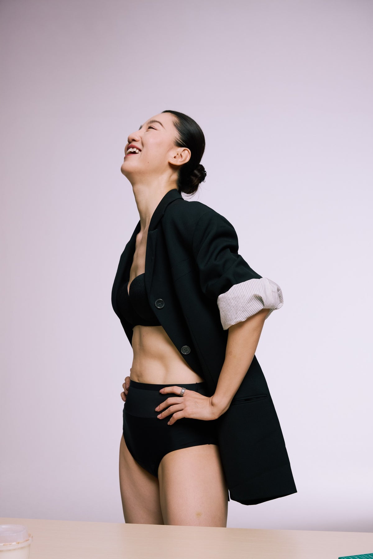 Laughing model wearing B.Peachy black underwear and an open blazer