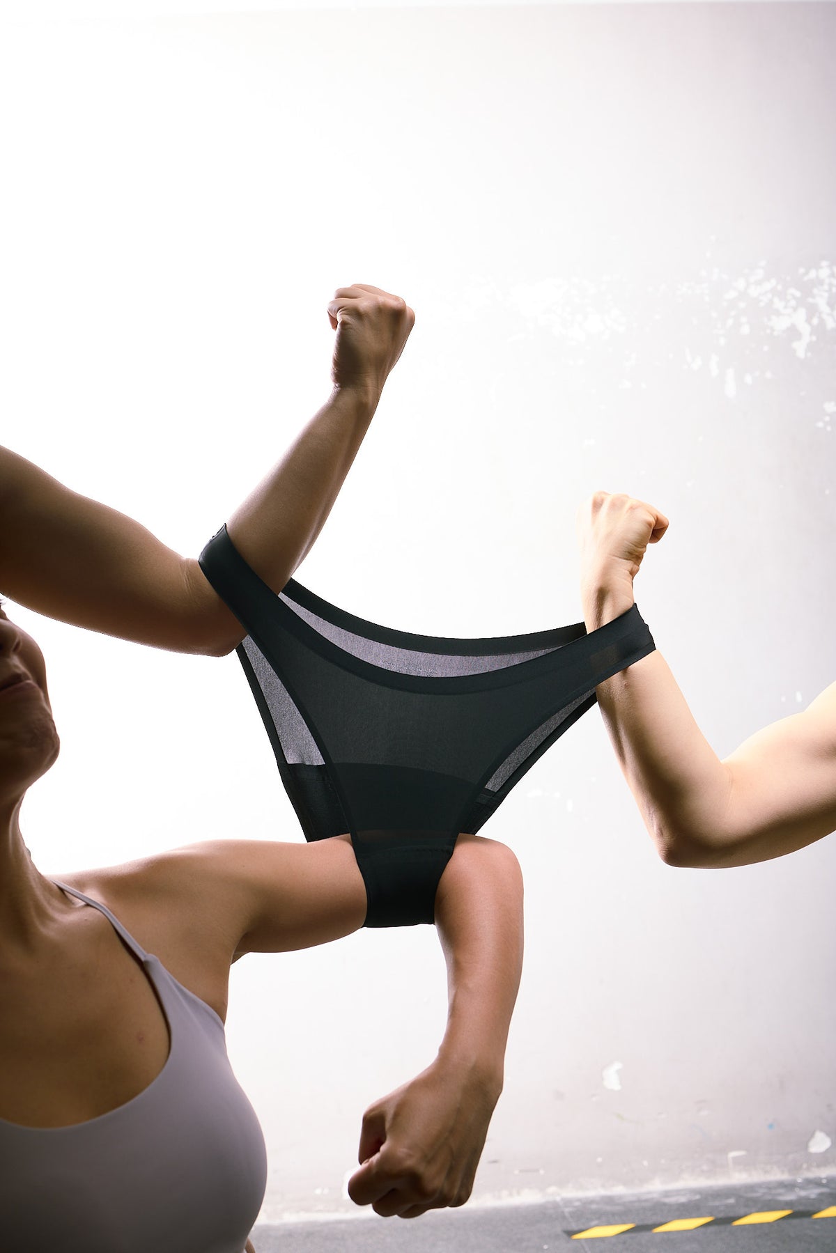 Two people stretching black Everyday Liner Cheeky Hipster underwear to show its lightweight fabric